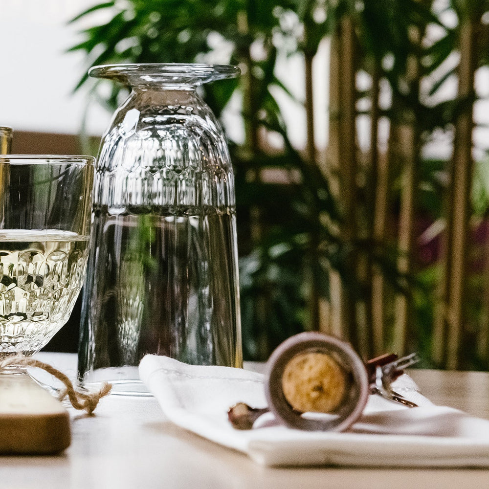 Table setting with wine bottle, glasses, and cheese board in a cozy indoor setting.